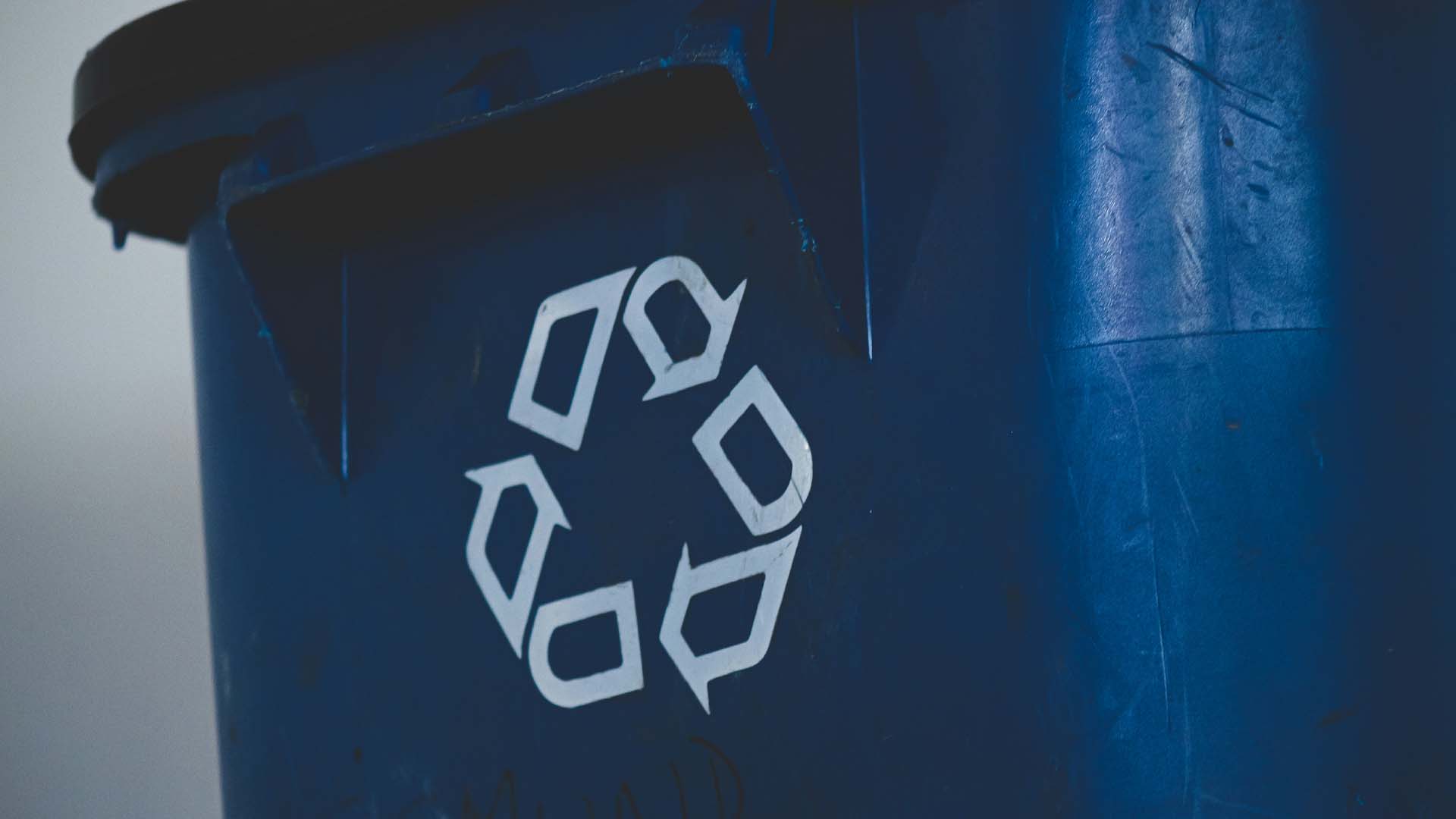 Recycling symbol printed on a blue recycling bin.